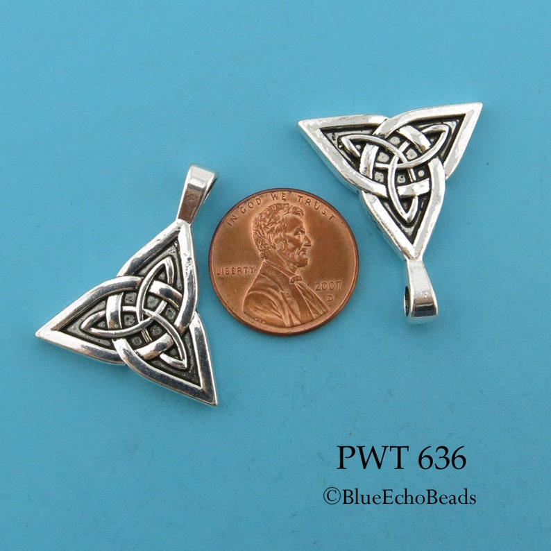 May include: Two silver-toned triangular Celtic knot pendants, one on top of the other, with a penny for scale. The pendant is about the size of a penny.
