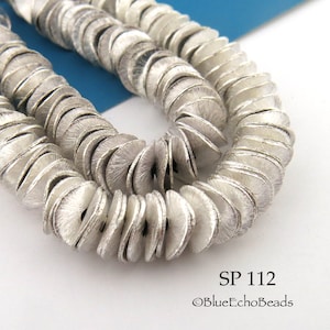 May include: Close-up of a strand of silver-colored, textured disc beads. The beads are arranged in a spiral pattern, with each disc slightly overlapping the next. The image includes the text "SP 112" and the copyright notice for "BlueEchoBeads."