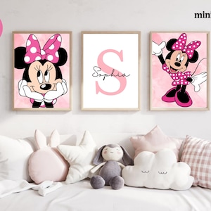 May include: Three framed Minnie Mouse prints in a child's room. The prints feature Minnie Mouse in various poses, a pink letter "S" with the name "Sophia", and are set against a pink background. The room is decorated with plush pillows and toys.