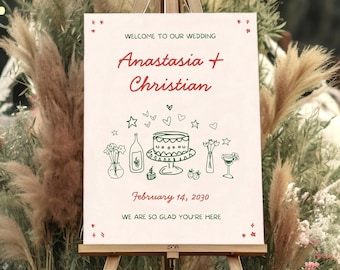 May include: A rectangular wedding sign on a wooden easel with a cream background and red text reading Welcome to our wedding, Anastasia + Christian, February 14, 2030, and We are so glad you're here, featuring green line art of a cake and drinks.