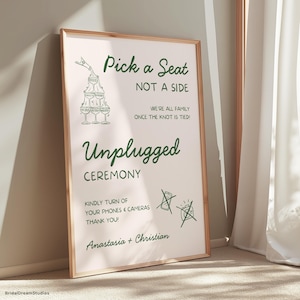 Puede incluir: Un letrero de boda enmarcado con el texto "Pick a Seat, Not a Side" y "Unplugged Ceremony". El letrero es de color rosa claro con texto verde y un marco dorado. También incluye los nombres "Anastasia + Christian".
