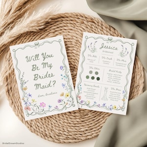 Może przedstawiać: Dwie karty zaproszeń z motywami kwiatowymi. Na jednej karcie widnieje napis "Will You Be My Bridesmaid?", a na drugiej szczegóły ślubu. Karty mają jasną zieloną obwódkę i są ozdobione kolorowymi kwiatami.