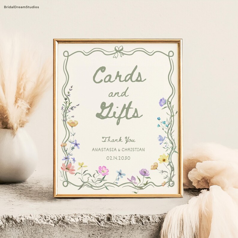 May include: A framed sign with the words "Cards and Gifts" in a soft green font. The sign is decorated with a floral border and includes the text "Thank You" and names and a date. The frame is gold.