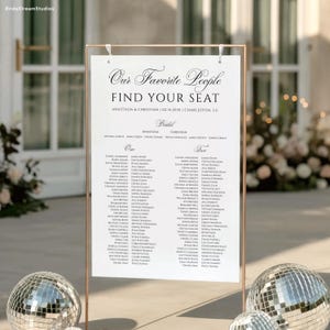 May include: A wedding seating chart with the text "Our Favorite People, Find Your Seat". The names of the guests are listed under the headings "Anastasia" and "Christian". The sign is displayed on a copper-colored frame.