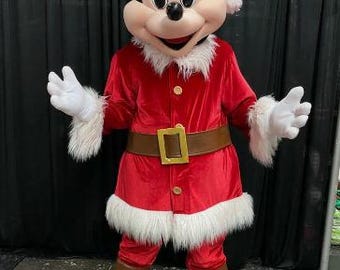 Op de afbeelding: Een rood en wit Mickey Mouse kostuum met een kerstmanmuts. Het kostuum heeft een rood fluwelen jasje met witte bontkraag, een bruine riem met een gouden gesp en een witte bontbroek.