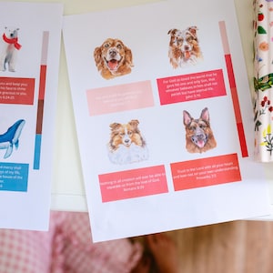 May include: Two white paper sheets featuring watercolor illustrations of animals including a polar bear, whale, and various dog breeds. Each animal is paired with a colored rectangular block containing printed Bible verses in English text.