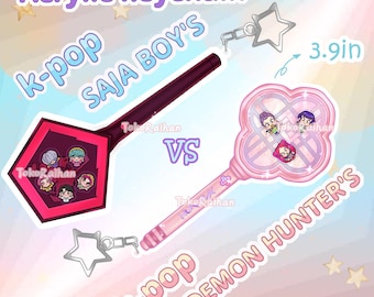 Pode incluir: Chaveiros de acrílico com designs K-pop. Um é um pentágono vermelho escuro, o outro tem formato de trevo rosa. Ambos têm ilustrações de personagens e pingentes em forma de estrela. O chaveiro rosa tem 9,9 cm de comprimento.