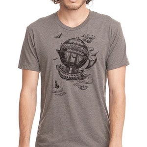 May include: A heather grey t-shirt featuring a black and white illustration of a steampunk airship with clouds and birds.
