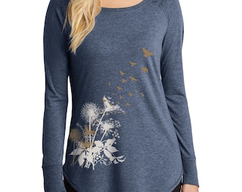 Könnte beinhalten: Ein langärmeliges, blaues T-Shirt mit einem weißen Löwenzahnmuster und Vögeln. Die Vögel sind hellbraun.