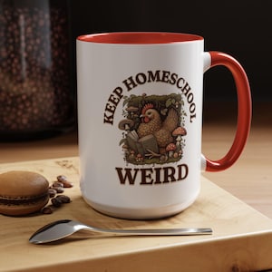 May include: White ceramic mug with a red rim and handle. The mug features a brown illustration of a chicken reading a book in a forest setting. The text "Keep Homeschool Weird" is printed in brown on the mug.