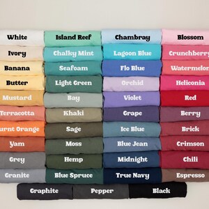 May include: A color chart displaying a variety of folded fabric samples. The chart includes a wide range of colors, from white and ivory to black and espresso. Each color is labeled with its name, such as "Island Reef," "Chambray," and "Berry."