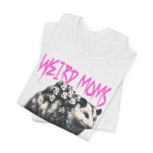 May include: A gray t-shirt with a black and white illustration of a possum with babies on its back. The text "WEIRD MOMS" is written in pink above the possum.