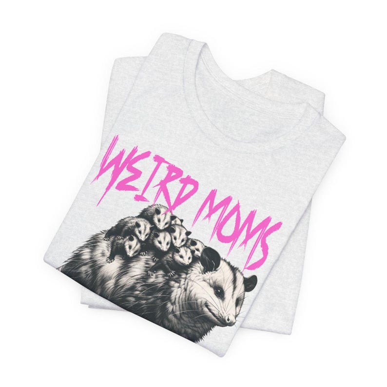 May include: A gray t-shirt with a black and white illustration of a possum with babies on its back. The text "WEIRD MOMS" is written in pink above the possum.