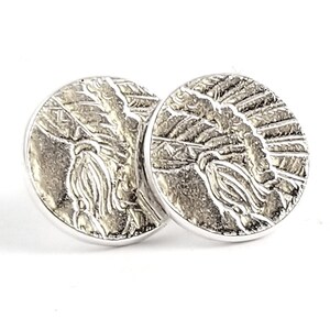 May include: A pair of silver stud earrings with a textured design. The design is a circular pattern with a raised center.