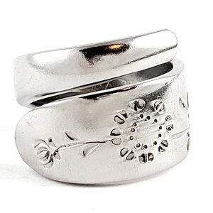 May include: A silver ring made from a recycled spoon, featuring a floral design with a flower and stem.