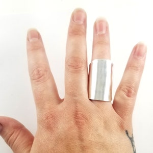 May include: A wide silver band ring with a smooth, polished finish.