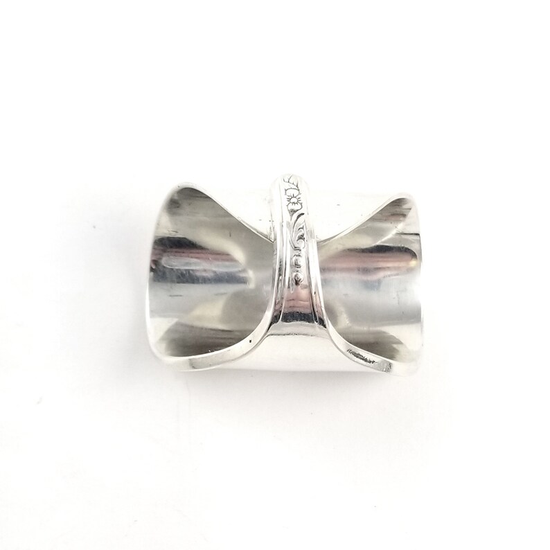 May include: A silver ring made from a repurposed spoon. The ring is wide and has a decorative design on the band.