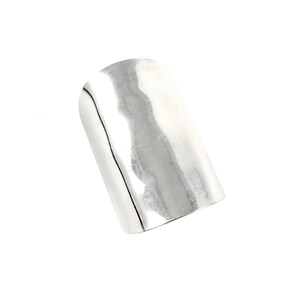 May include: A silver ring with a hammered finish. The ring is wide and flat, and has a rounded edge.