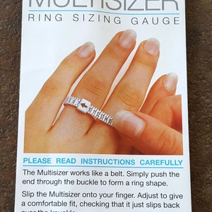 May include: A white plastic ring sizer with a black arrow and numbers from 4 to 15. The sizer is being used to measure a finger. The text "PLEASE READ INSTRUCTIONS CAREFULLY" is printed on the card. The Multisizer works like a belt. Simply push the end through the buckle to form a ring shape. Slip the Multisizer onto your finger. Adjust to give a comfortable fit, checking that it just slips back over the knuckle. When best fit is achieved, read off size indicated by the arrow. (size 7 shown)