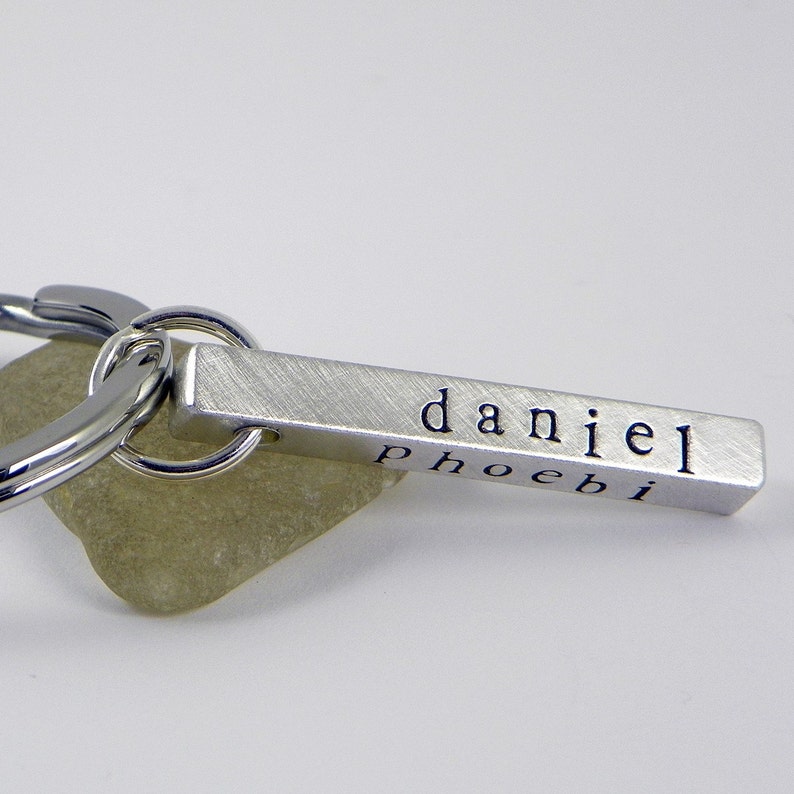 May include: Silver keychain with a bar engraved with the names "daniel" and "phoebi".