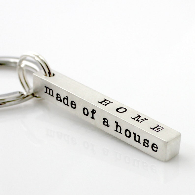 May include: Silver keychain with a bar charm that reads "HOME made of a house".