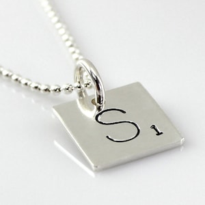 May include: A silver necklace with a square pendant featuring the letter "S" and the number "1" engraved on it.