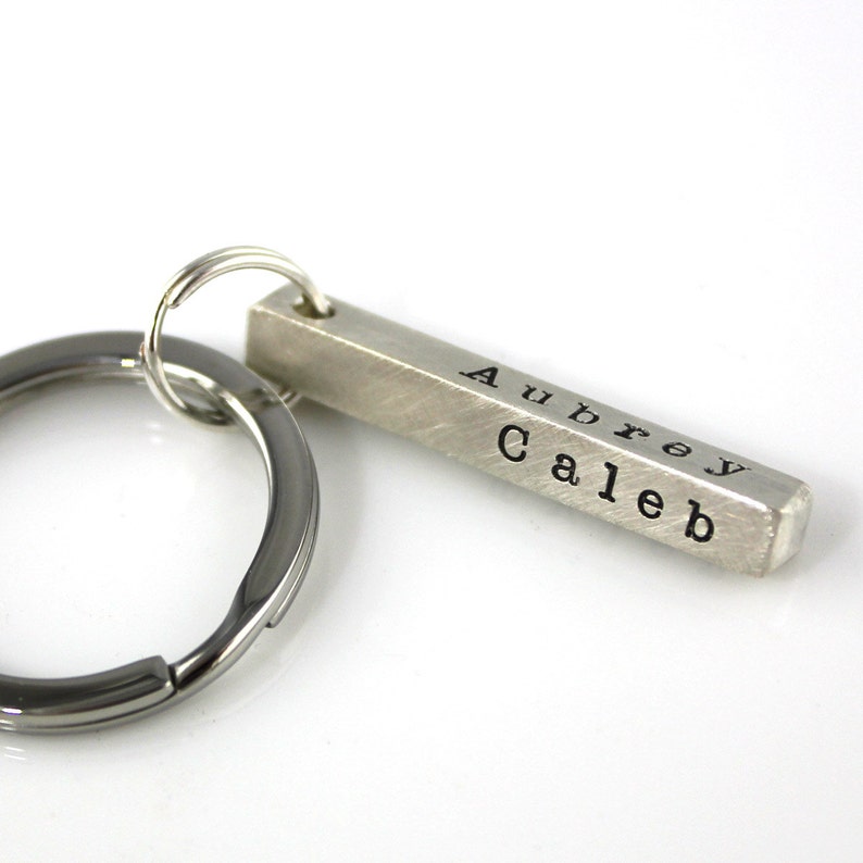 May include: Silver bar keychain with the names Aubrey and Caleb engraved on it.