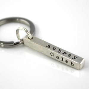 May include: Silver bar keychain with the names Aubrey and Caleb engraved on it.
