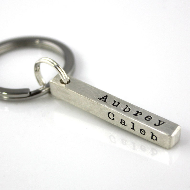 May include: Silver bar keychain with the names Aubrey and Caleb engraved on it.