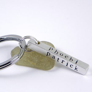 May include: Silver keychain with a bar charm engraved with the names "phoebi" and "patrick".