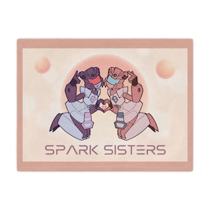 May include: A rectangular throw blanket featuring a graphic illustration of two stylized robots in purple and pink tones. The robots are kneeling and forming a heart shape with their hands. The text SPARK SISTERS is printed in a bold font below.
