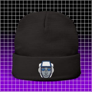 May include: Black beanie hat with a robot face embroidered on the front. The robot face is gray with white and blue accents. The hat is made of a soft, knitted material.