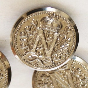 May include: Silver-toned metal buttons with a raised design featuring a crown and the letter "N".