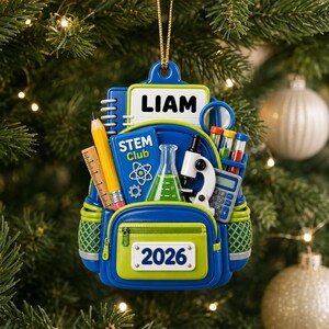 May include: A blue and lime green backpack-shaped ornament featuring the name LIAM, the text STEM Club, and the year 2026. The design includes a yellow pencil, a ruler, a green liquid-filled flask, a white microscope, and a blue calculator.