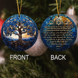 May include: A round, blue Christmas ornament with a gold string. The front features a tree design with blue leaves and a brown trunk. The back has text and a Star of David. The text reads "Let no sadness come through this gate."