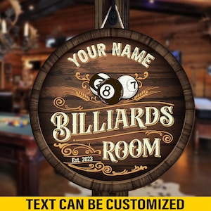 May include: A round wooden sign with the words "YOUR NAME" at the top, and "BILLIARDS ROOM" in the center. The sign features a design with billiard balls, wheat stalks, and the text "Est. 2023". The bottom of the sign reads "TEXT CAN BE CUSTOMIZED".