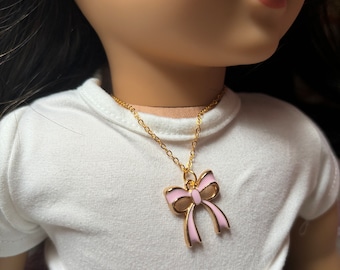 May include: A gold chain necklace with a pink enamel bow pendant.