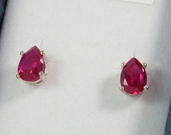 May include: A pair of silver stud earrings with pear-shaped red gemstones.
