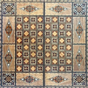 Könnte beinhalten: Ein detailliertes, quadratisches Holzspielbrett mit eingelegten geometrischen Mustern. Das Brett hat ein zentrales Raster aus Quadraten und dekorative Bordüren mit Rauten- und Dreiecksdesigns in Braun-, Beige- und dunklen Holztönen.