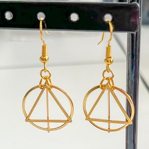 May include: Gold geometric earrings with a circle and triangle design. The earrings are dangle style with a hook closure.