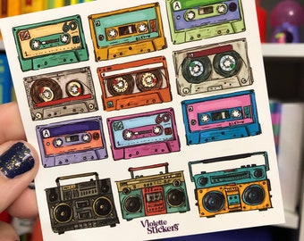 May include: A sheet of colorful stickers featuring vintage cassette tapes and boomboxes. The stickers are designed in a retro style with a hand-drawn aesthetic. The text "Violette Stickers" is printed at the bottom of the sheet.