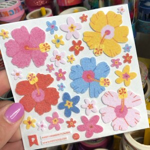 May include: A sheet of fuzzy Hawaiian flower stickers with pink, yellow, blue, and red flowers. The stickers are on a white background and have the text "Fuzzy Hawaiian Flowers" and "www.papsticks.com" printed on them.