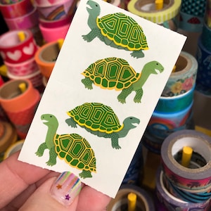 May include: A sheet of stickers with four green and yellow turtles. The turtles have a patterned shell and are facing different directions.