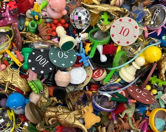 May include: A large collection of colorful plastic and metal trinkets, including toy dinosaurs, game pieces, and small toys. There are also several small mirrors, a disco ball, and a few poker chips with the numbers 10, 20, 50, and 100 on them.