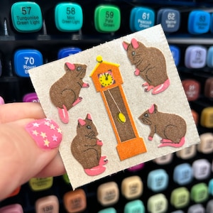 May include: A sheet of brown felt stickers with four brown mice and a brown and orange clock. The stickers are on a white background.