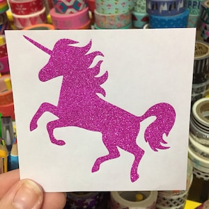 May include: A pink glitter unicorn silhouette on a white background. The unicorn is standing on its hind legs with its head turned to the side.
