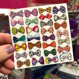 May include: A sheet of colorful bow tie stickers with various patterns and designs. The stickers are arranged in rows on a white background. The sheet is labeled "Violette Stickers".