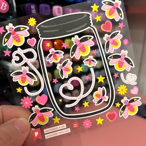 May include: A clear sticker sheet featuring a jar design filled with colorful stars and fireflies. The fireflies have pink wings and yellow abdomens. Additional elements include pink hearts, yellow stars, and pink flowers. The text "LIGHTNING IN A JAR" and "WWW.PIPSTICKS.COM" are visible.