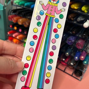 May include: A sticker featuring a cartoon clown with a pink and white outfit, juggling colorful balls. The clown is standing on stilts with rainbow stripes. The sticker says "STILTS & STRIPES" and "www.PIPSTICKS.COM".