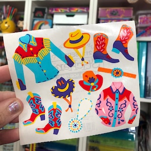 May include: A sheet of colorful stickers featuring a variety of western-themed clothing and accessories. The stickers include a blue and red cowboy shirt, a pink and blue cowboy shirt, a yellow cowboy hat, a purple cowboy hat, a pair of red cowboy boots, and a pair of blue cowboy boots.
